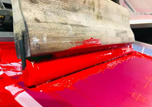 Independent Vinyl & Screen LLC screen printing squeegee on press with red plastisol ink lucas, iowa