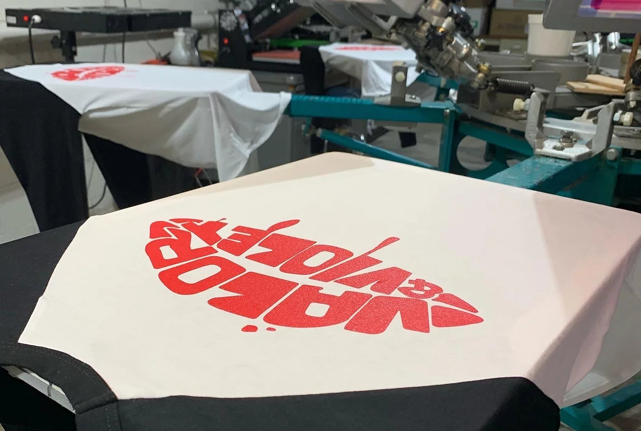 Independent Vinyl and Screen LLC screen printed t tee shirt with bright red design on front with garments on press in production